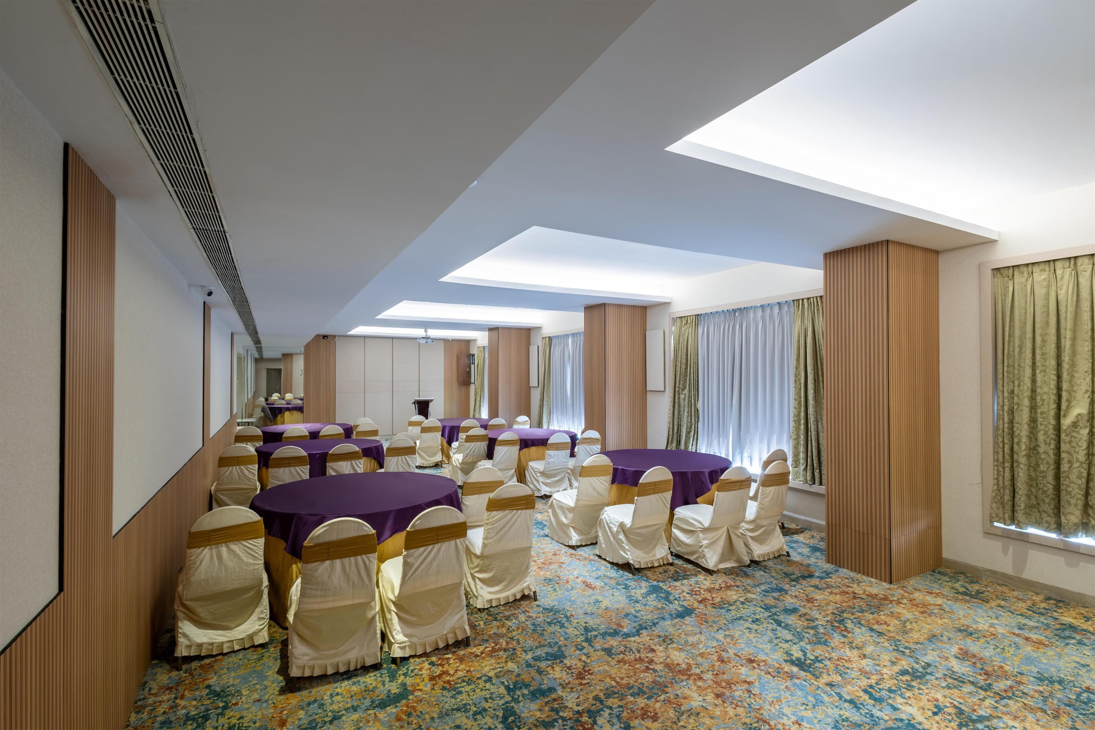 A conference room with tables and chairs, large windows, and a patterned carpet.