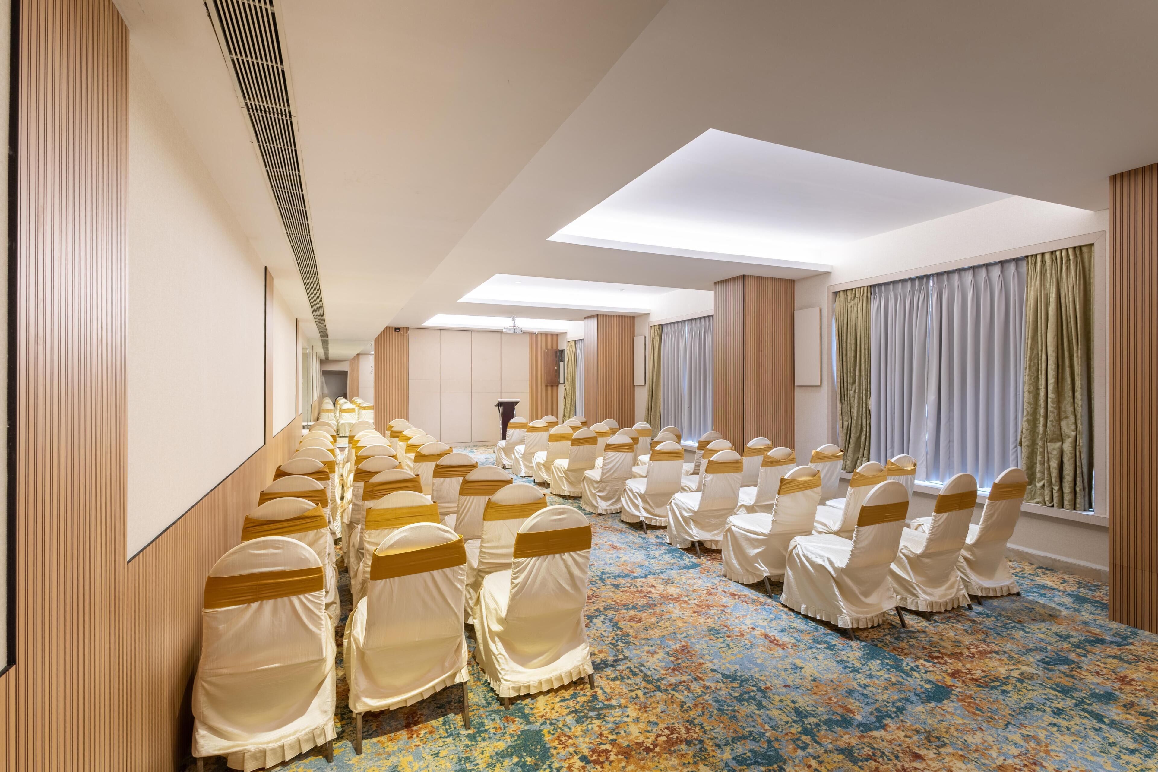 Ein Konferenzraum mit Reihen von Stühlen, einem gemusterten Teppich und einer hohen Decke mit Oberlichtern.