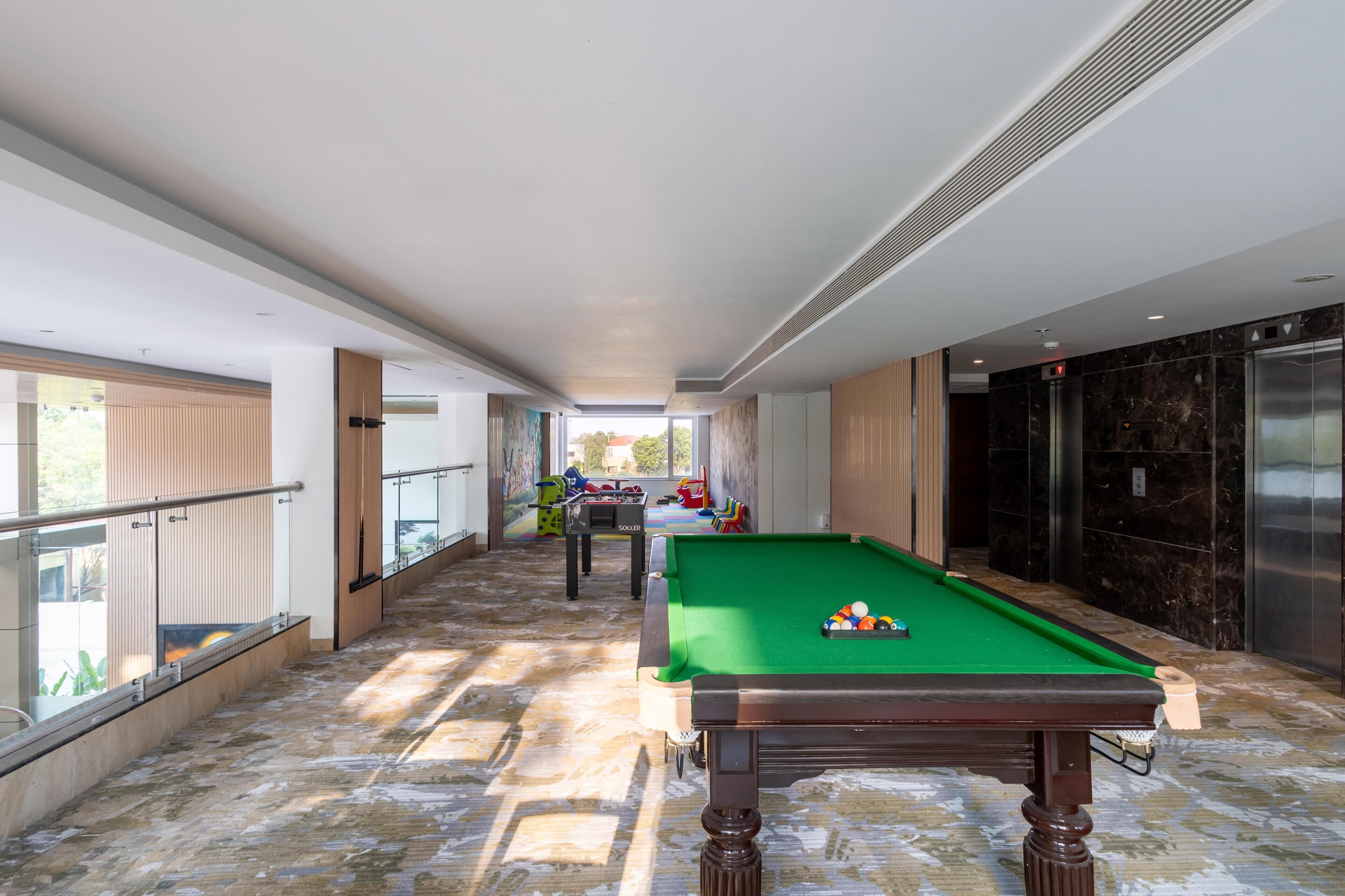 Une table de billard dans un couloir, avec vue sur un balcon.
