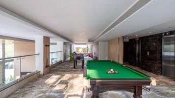 Une table de billard dans un couloir, avec vue sur un balcon.
