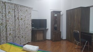 A room with a bed, a TV, a wardrobe, and a chair. - Kharadi EON IT NP Hospitality (Pune)