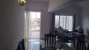 A dining area with a glass table, chairs, and a ceiling fan. - Kharadi EON IT NP Hospitality (Pune)