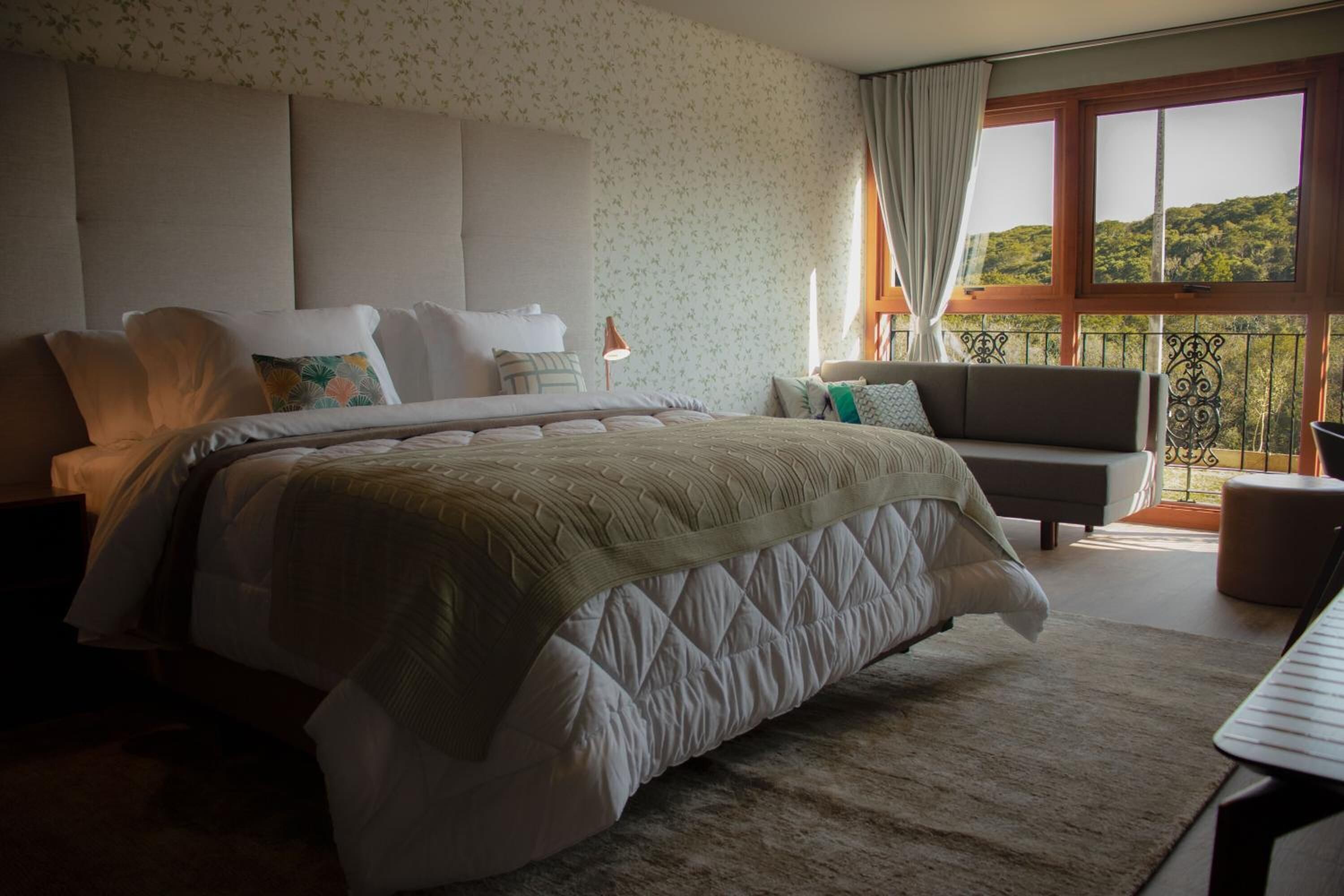 Een slaapkamer met een groot bed, een bank en uitzicht op een balkon.