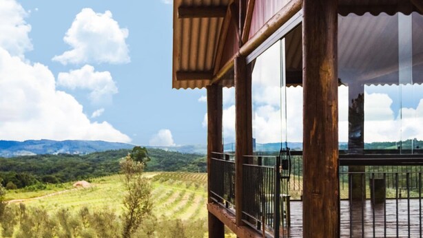 A wooden balcony with a view of a green landscape and mountains. - Hotel Vinícola Davo (Ribeirão Branco)