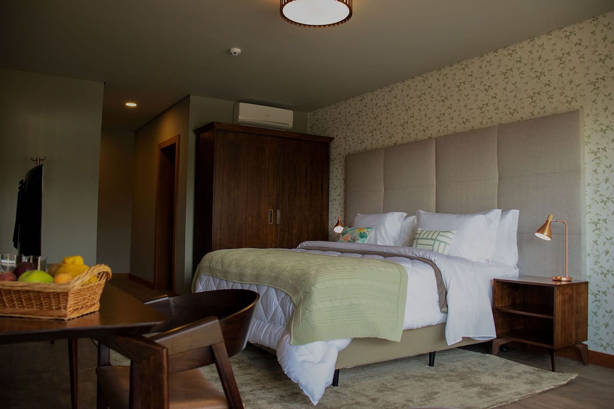 Une chambre à coucher avec un lit, une table de chevet, une lampe et une armoire en bois.