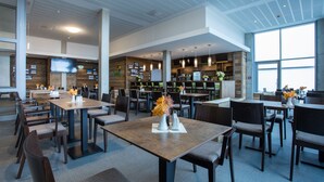 A modern restaurant with high ceilings, wooden accents, and a variety of seating arrangements. - Sportpark Rabenberg (Breitenbrunn/Erzgeb.)