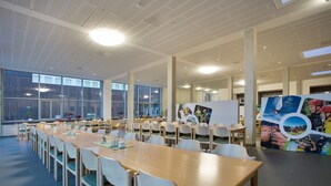 A conference room with long tables, chairs, and large windows. - Sportpark Rabenberg (Breitenbrunn/Erzgeb.)