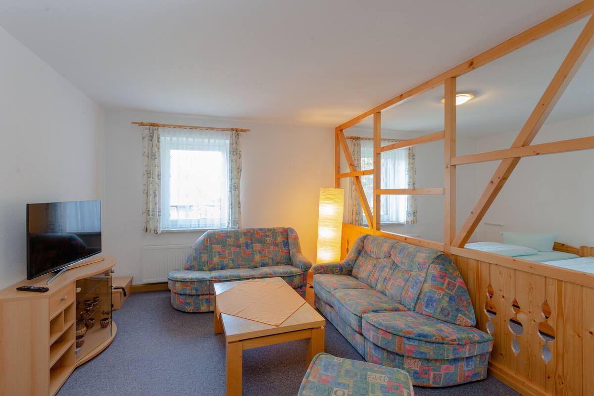A cozy living room with a sofa set, a television, and a wooden partition.