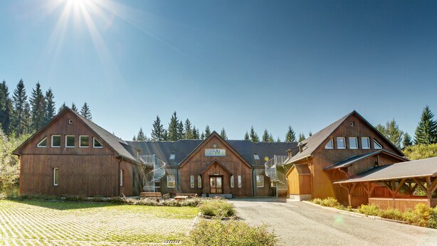 A large wooden building with a central entrance, two side wings, and a covered area with stairs. - Sportpark Rabenberg (Breitenbrunn/Erzgeb.)