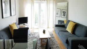 Un soggiorno moderno con un divano, un tavolino, una TV e un balcone con tende.