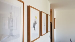 Un corridoio con opere d'arte incorniciate appese al muro, tra cui schizzi di una torre dell'orologio e una figura su una bicicletta.