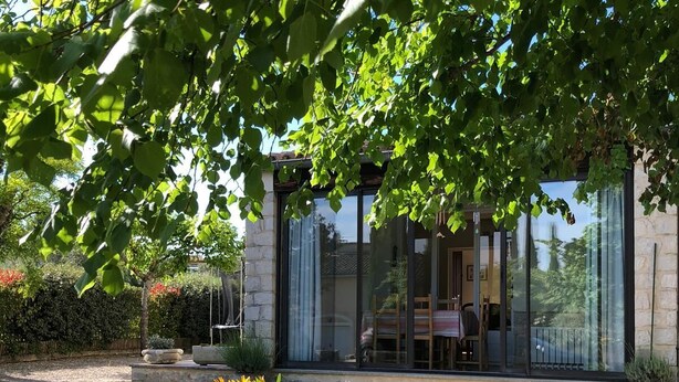Un bâtiment moderne doté de grandes fenêtres, d’une façade en pierre et d’une allée gravillonnée.