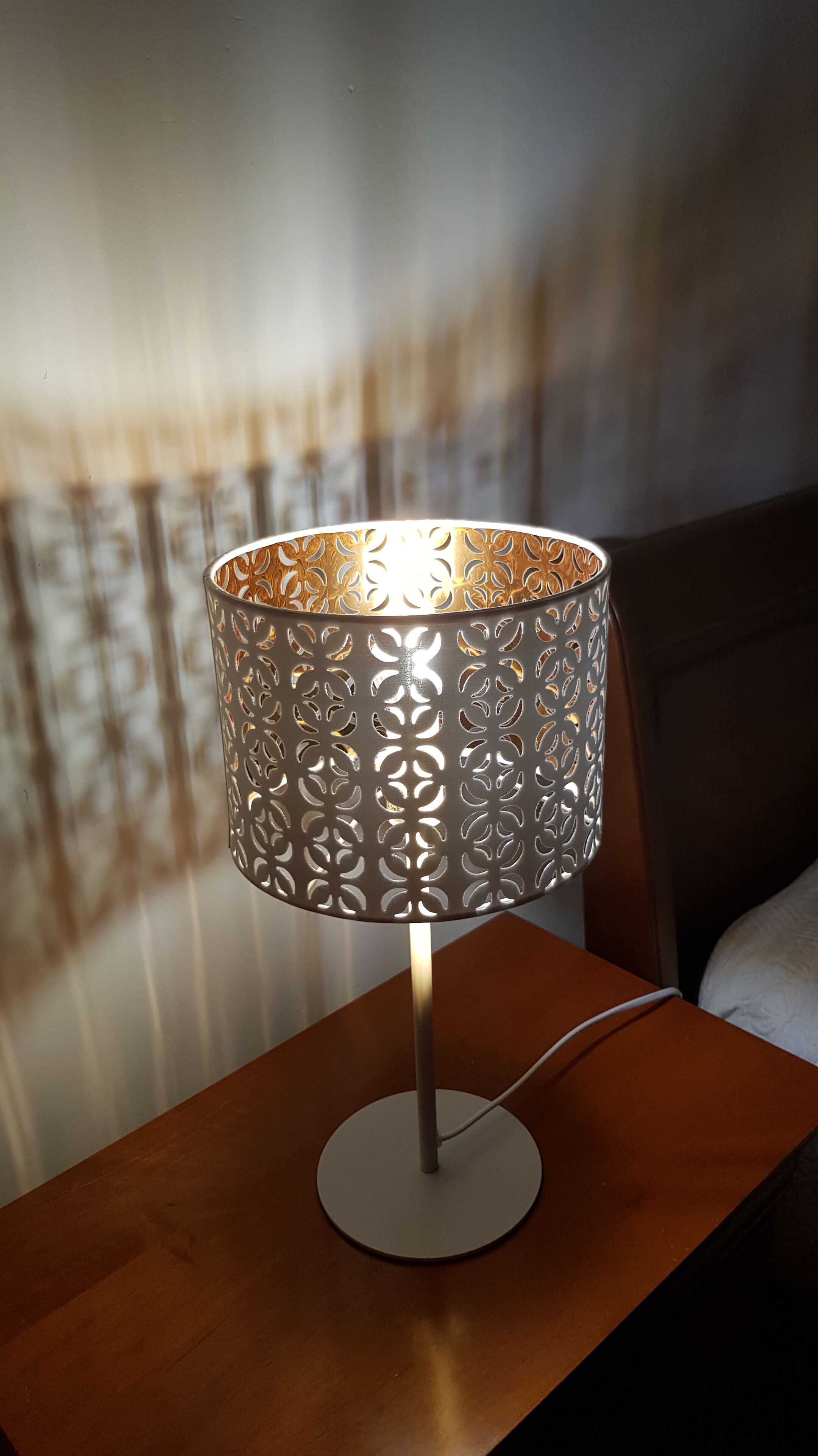 A table lamp with a decorative metal shade on a wooden nightstand.