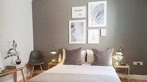 Una camera da letto ordinata con un letto grande, due comodini, una sedia e decorazioni alle pareti.