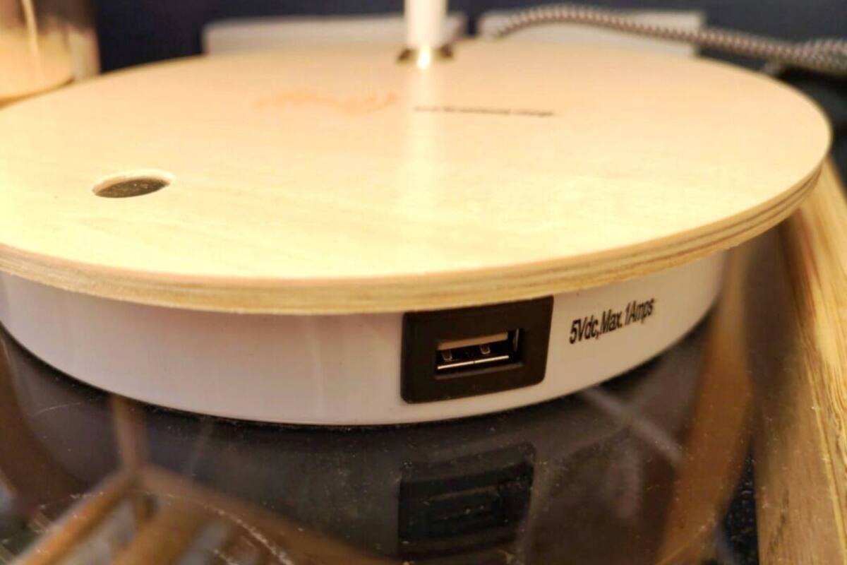 A white portable device with a USB port and a label reading "5Vdc, Max 1A".