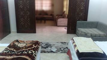 A room with two beds, a sofa, and a patterned rug.