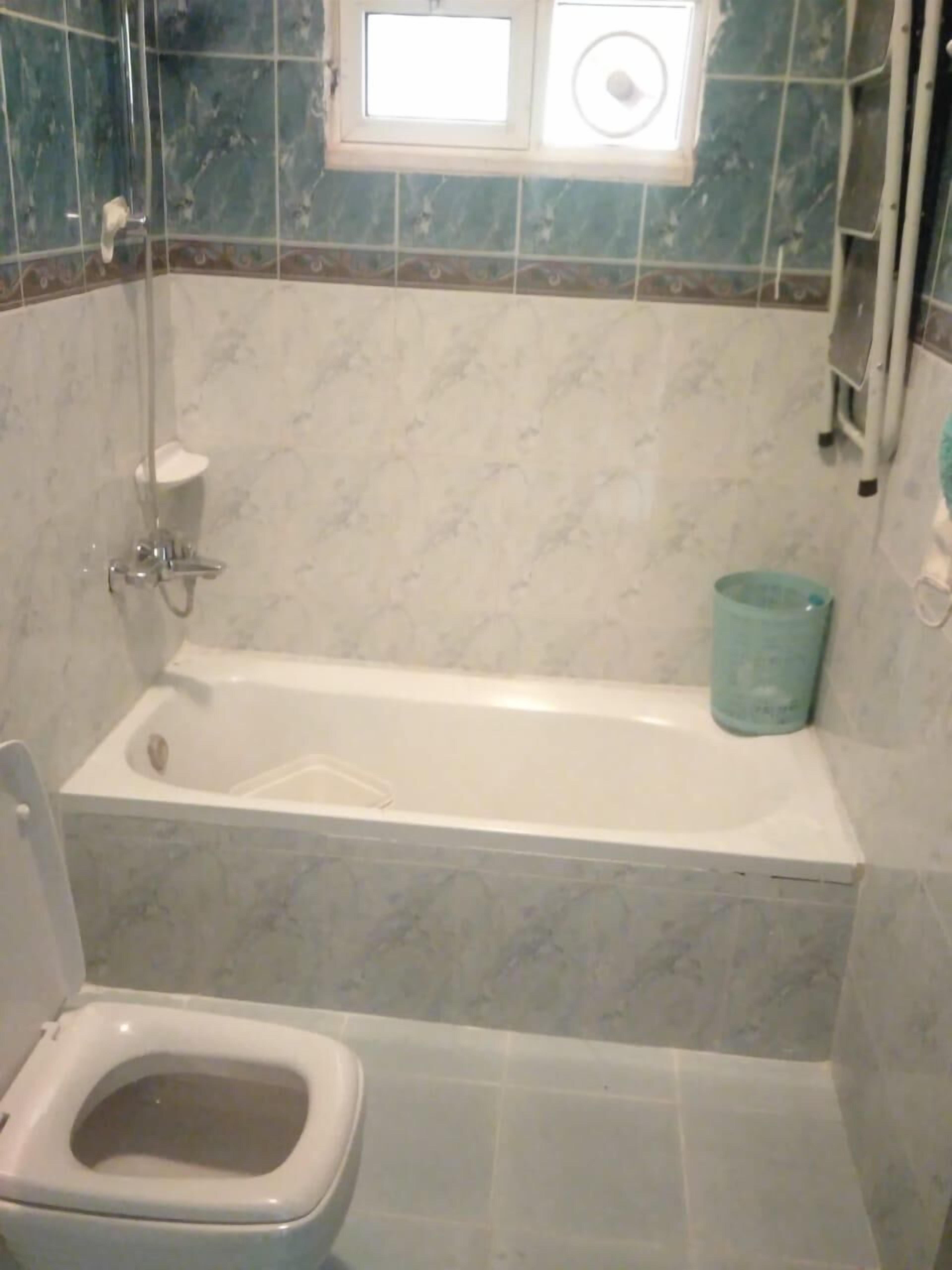 Une salle de bain avec une baignoire, des toilettes et une fenêtre.