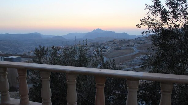 A balcony with a view of a valley and distant mountains.
