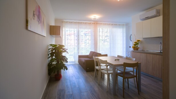 A modern kitchen with a dining area, wooden cabinets, and a potted plant. - Appartamento Molo B (Portoferraio)