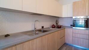 A modern kitchen with a stainless steel sink, wooden cabinets, and a built-in oven. - Appartamento Molo B (Portoferraio)