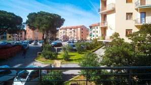 A residential street with parked cars, apartment buildings, and a pedestrian walking. - Appartamento Molo B (Portoferraio)