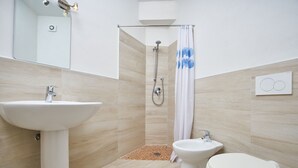 Un baño moderno con lavamanos pedestal, inodoro y ducha.