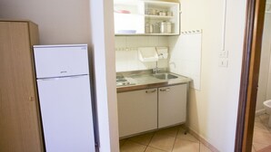 Une cuisine de taille réduite, équipée d’un réfrigérateur, d’un évier et de placards.