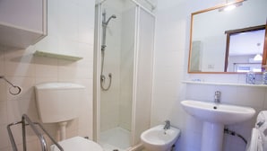 Une salle de bain comprenant des toilettes, un bidet, une douche et un lavabo.