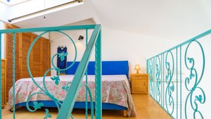 A bedroom with a bed, wooden wardrobe, and a decorative metal railing. - Appartamento Poggio Al Sole (Capoliveri)