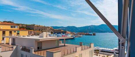 A coastal building with a rooftop terrace overlooking a marina with boats.
