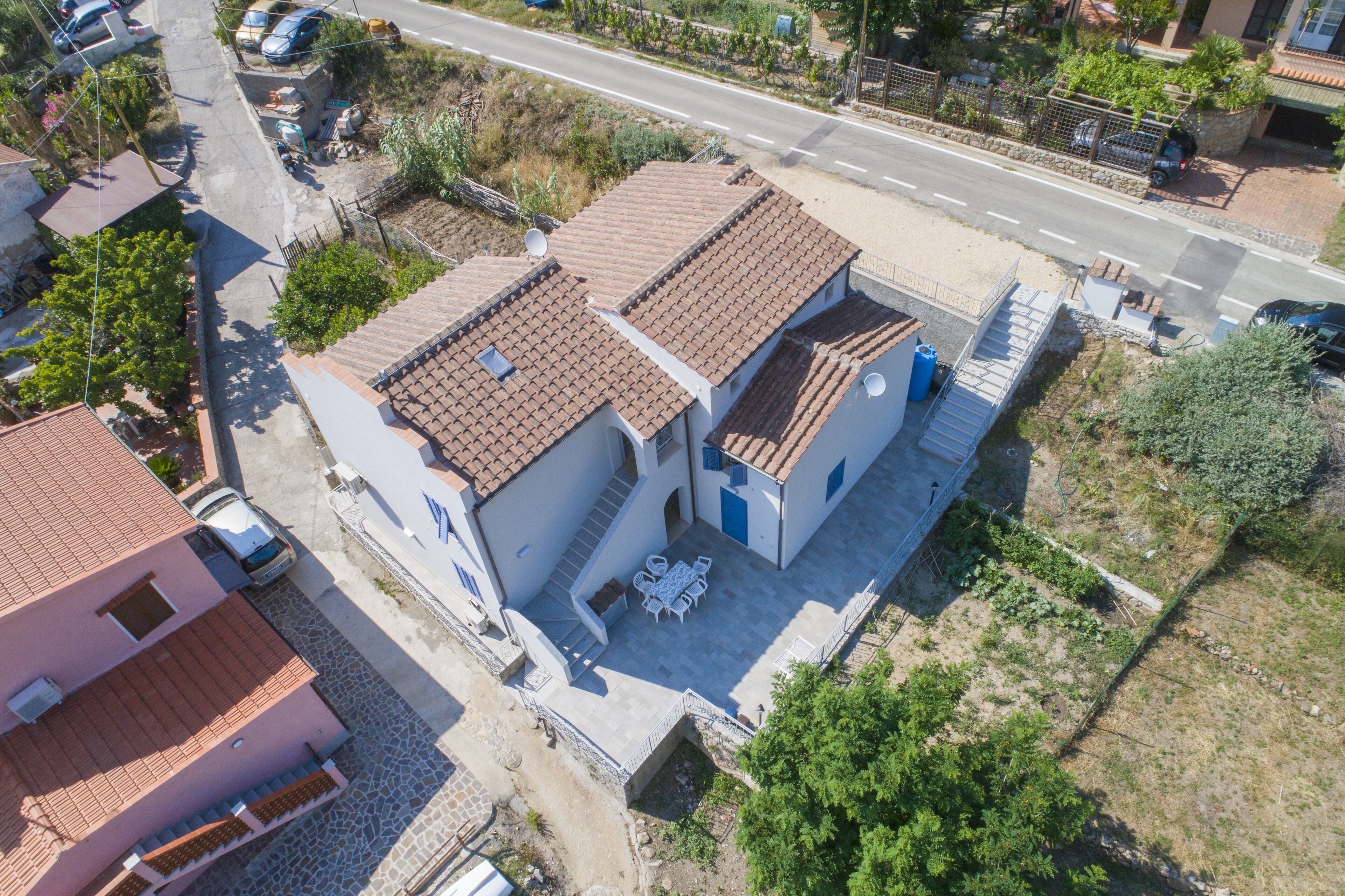 A residential building with a tiled roof, a patio with outdoor furniture, and a satellite dish.