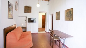 Ein Zimmer mit Holzboden, einer Couch, einem Tisch mit Stühlen und gerahmten Bildern an den Wänden.