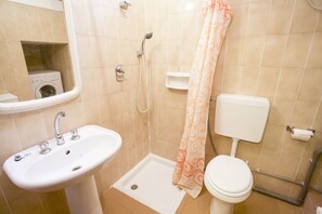 Un bagno con lavandino, servizi igienici, doccia e una lavatrice nell'angolo.