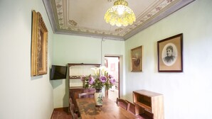 Een eetkamer met een houten tafel, stoelen, een vaas met bloemen, ingelijste foto's aan de muur en een kroonluchter.