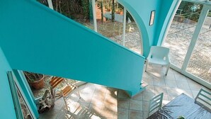 Un interior turquesa con un patio empedrado, una mesa de madera y una planta en maceta.