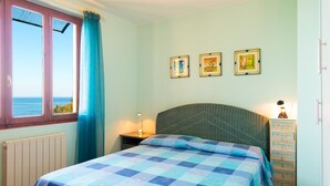 Een slaapkamer met een bed, nachtkastje, dressoir en een raam met uitzicht.