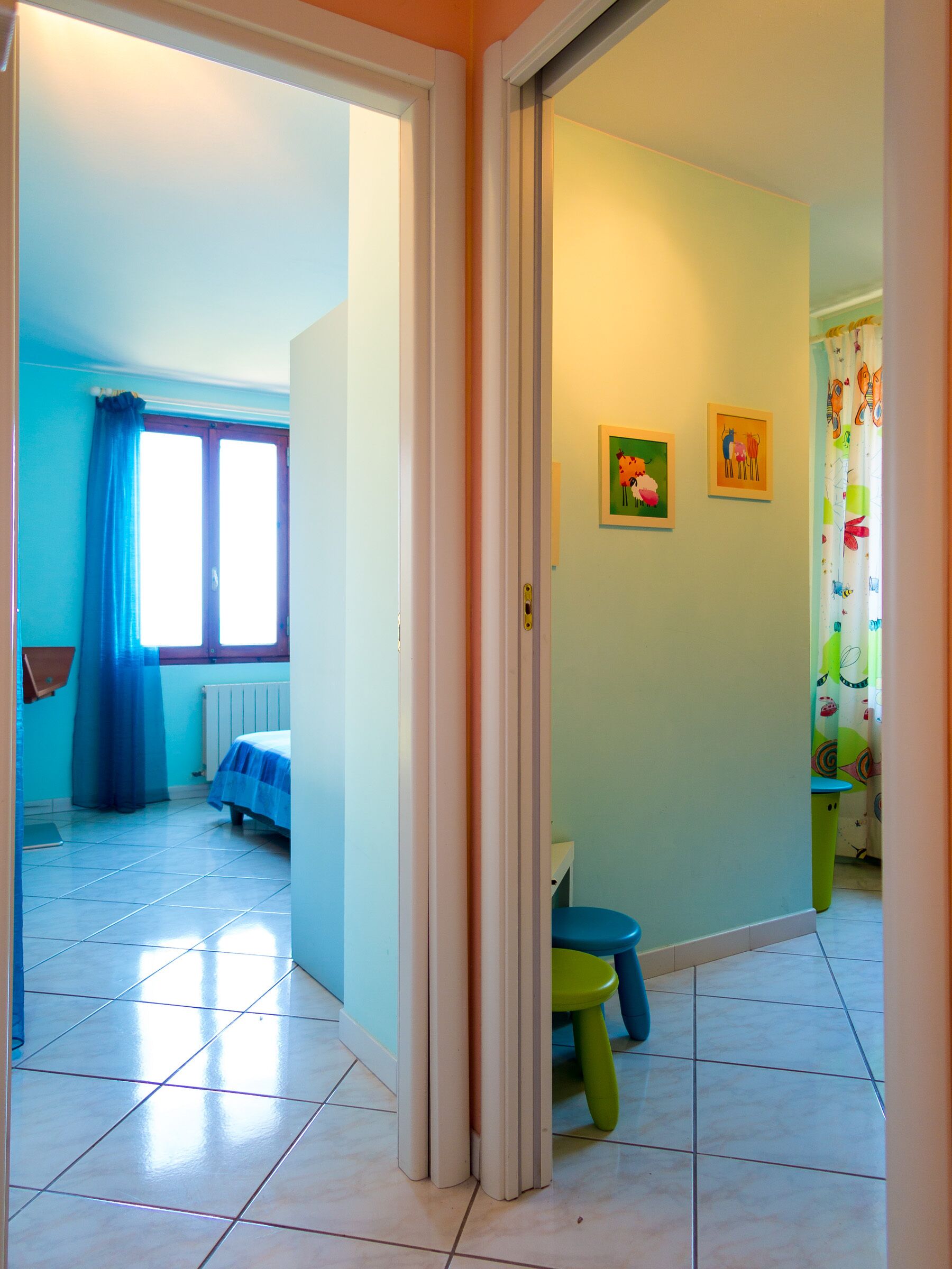 A room with a bed, a window with curtains, and a door leading to another room.