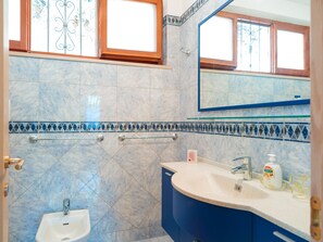 A bathroom with a sink, mirror, and window.