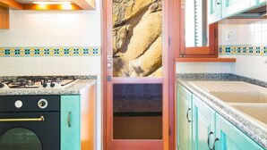 A kitchen with a gas stove, a built-in oven, and teal cabinets. - Villino Forno (Portoferraio)