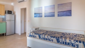 A bedroom with a bed, a small bedside table, and a wall-mounted air conditioner. - Appartamenti Panorama (Portoferraio)