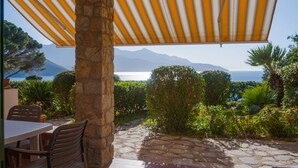 A stone pillar, a table with chairs, and a view of the sea and mountains. - Appartamenti Panorama (Portoferraio)