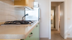 A kitchen with a gas stove, a microwave, and a water faucet. - Appartamenti Panorama (Portoferraio)
