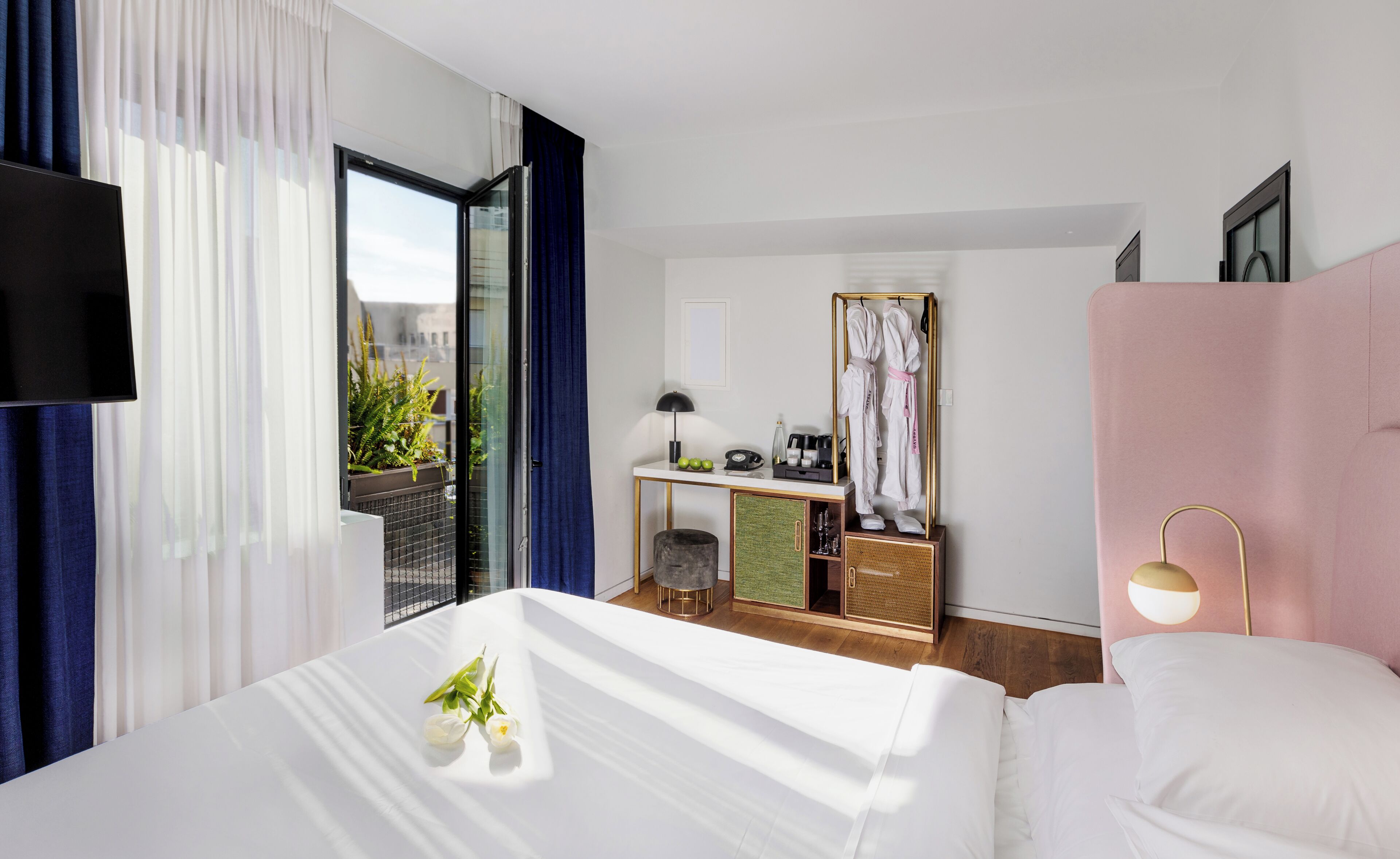 A hotel room with a bed, a desk, a chair, a mirror, and a window with curtains.