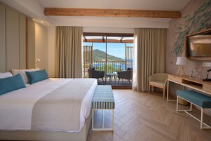 Habitación de hotel con una cama grande, un escritorio, una silla y vista al mar.