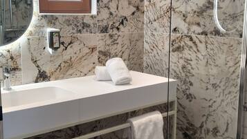 Une salle de bain moderne avec un pare-baignoire en marbre, une douche en verre et un lavabo blanc.