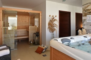 Un cuarto de spa con una sauna de madera, un jacuzzi y una zona de masajes con paredes de vidrio.