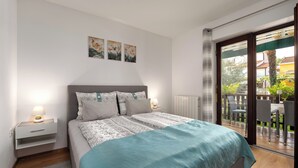 Une chambre moderne avec un lit, des tables de chevet et une vue sur le balcon extérieur.