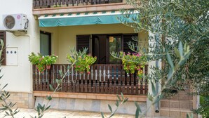 Un immeuble doté d’un balcon, d’un auvent vert et de plantes en pot.