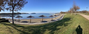 Un parco sul lago con sentieri pedonali, ombrelloni e alberi.