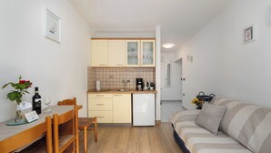 Ein kompakter Wohnbereich mit Essplatz, einer Küchenzeile und einer Couch.